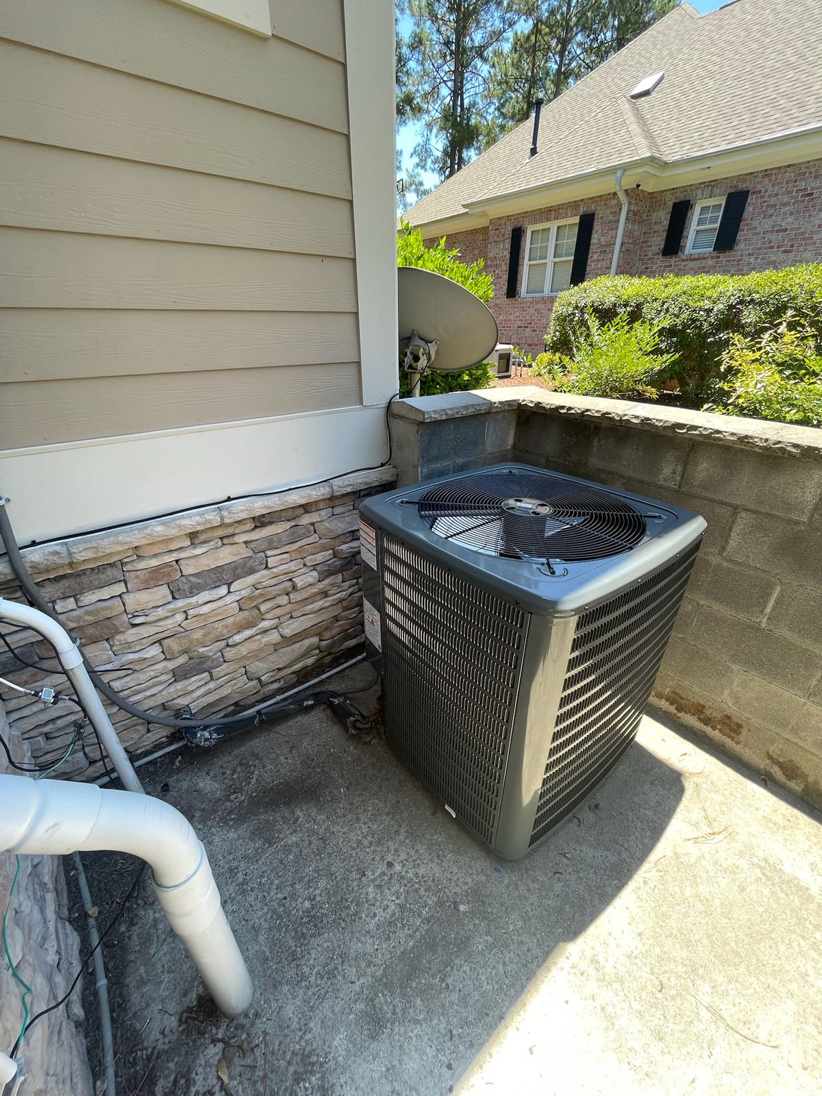 A Danny's Heating and Air technician completing a condenser install beside a brick home in Wilmington