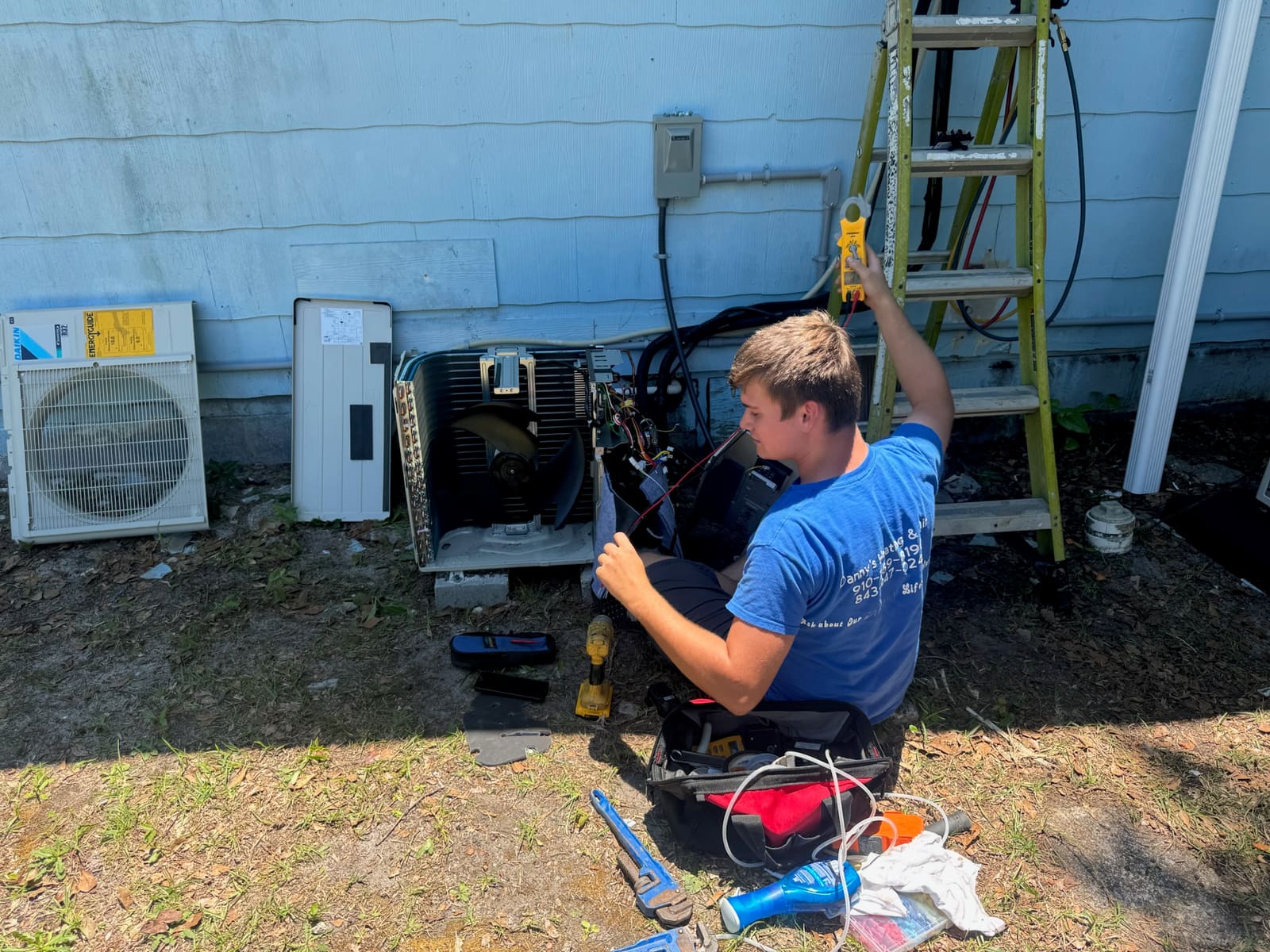 Danny's technician in branded blue shirt repairing a residential outdoor condenser unit